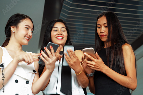 Three women friends having conversation while looking at mobile phone in their hands. Concept of social media, gossip news and online shopping. uds