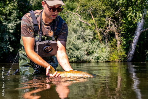 Man releasing trout back into river after catch