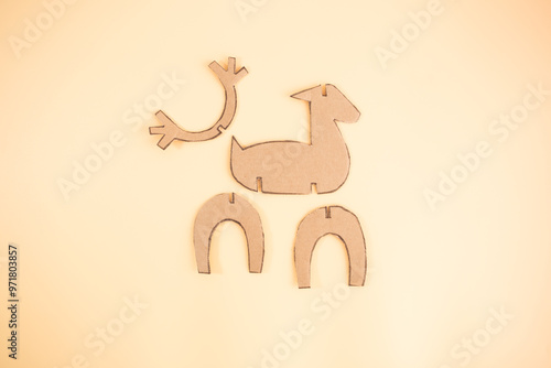 Brown cardboard pieces arranged for reindeer craft, including body, head, and legs. Ideal for showcasing recycled paper use in creative, eco friendly projects, photo