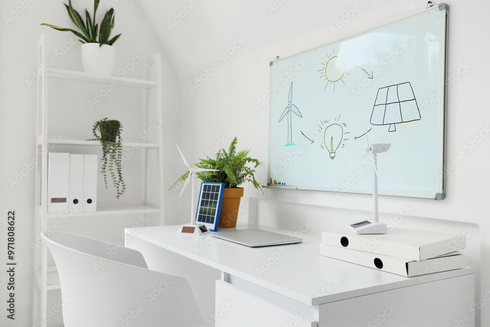 Fototapeta premium Engineer's workplace with wind turbine models and whiteboard in office