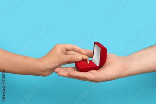 Young man proposing to his girlfriend on blue background photo