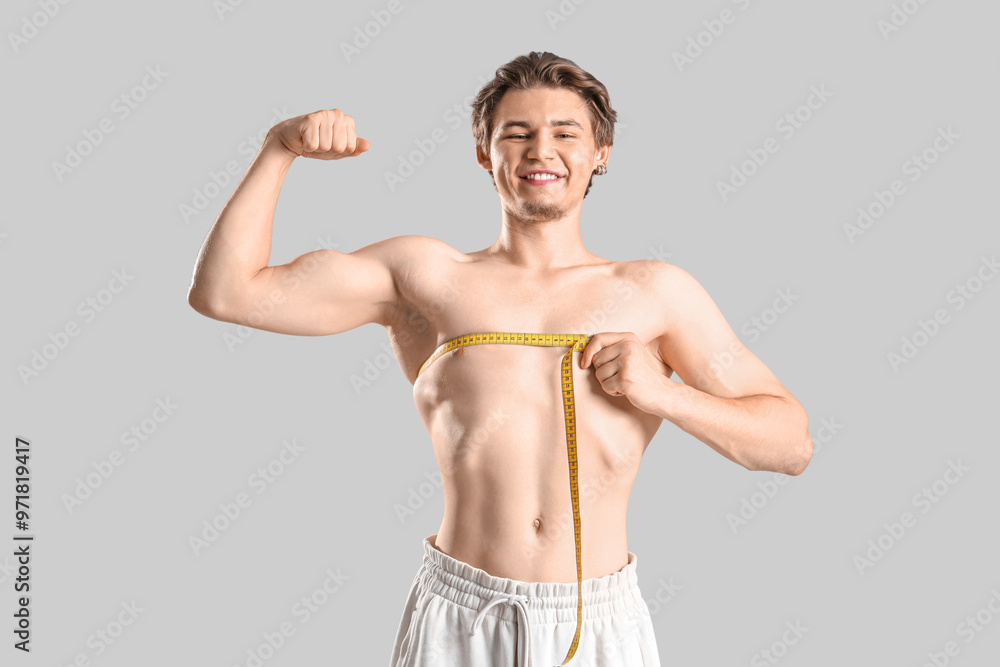 Young man measuring his chest on light background. Weight loss concept