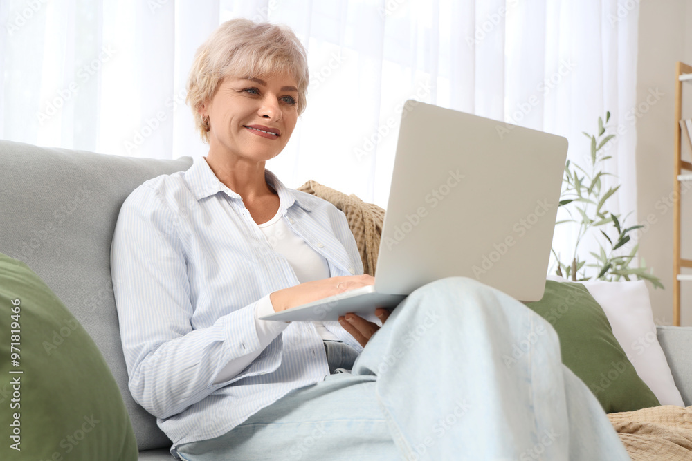 Mature woman using laptop on sofa at home Mature woman using laptop on sofa at home