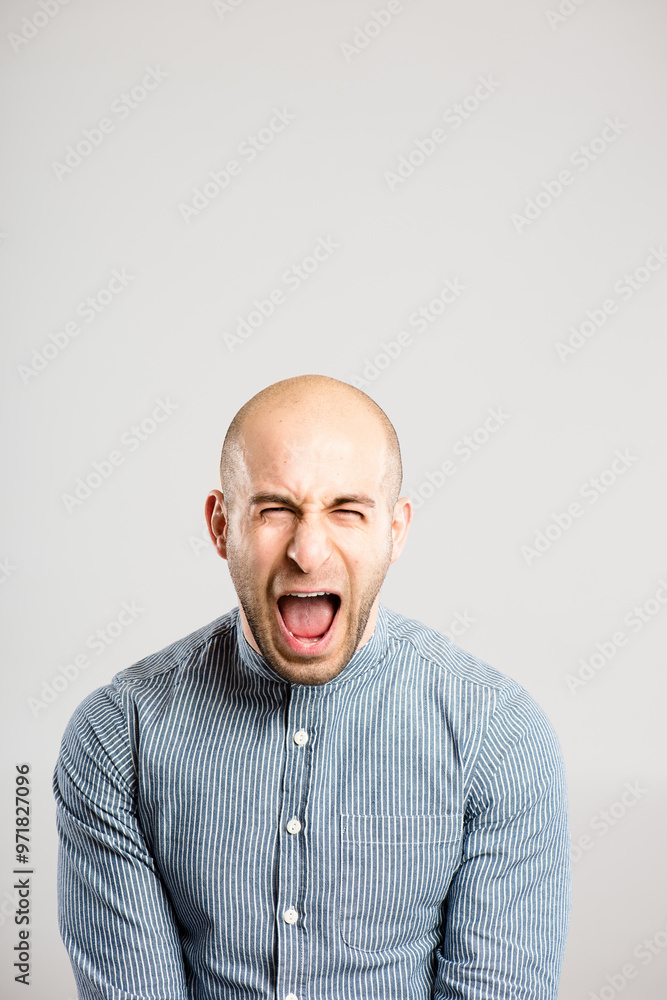 Obraz premium Shouting, screaming and portrait of angry man in studio with anger, upset and crazy reaction. Body language, facial expression and isolated person with loud noise, voice and comic on gray background