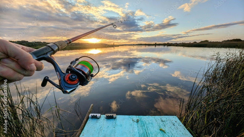 Hand holding fishing rod and reel, sunset fishing at Corrib river at Galway, Ireland, spinning, angling, catch and release, sport and leisure, nature background