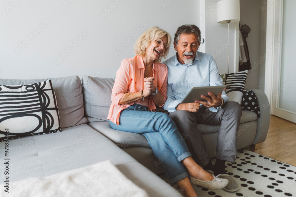 Senior couple sitting on the couch talking to their family over a video call Senior couple sitting on the couch talking to their family over a video call