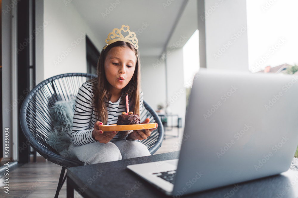 Young girl blowing a birthday candle while on video call with her grandparents Young girl blowing a birthday candle while on video call with her grandparents