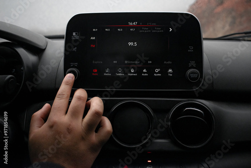 Detail of a hand turning on the radio in his modern car