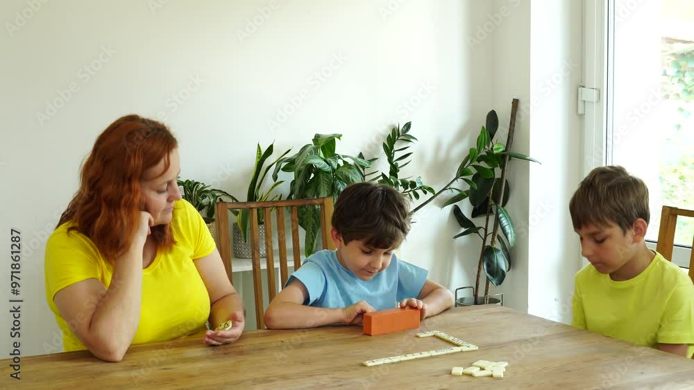 Mother shows kids how to play domino, board game and time together Mother shows kids how to play domino, board game and time together