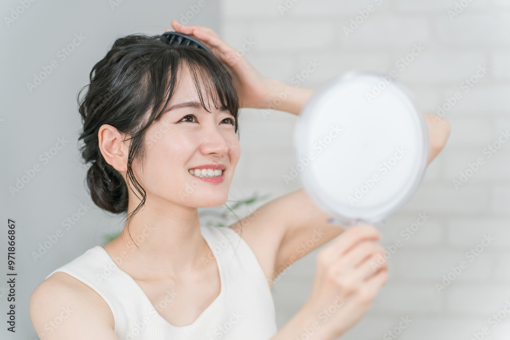 鏡を見ながら頭皮マッサージをするアジア人女性
