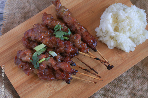 Foto Grilled pork skewers or moo ping eat with Sticky rice on wooden cutting board