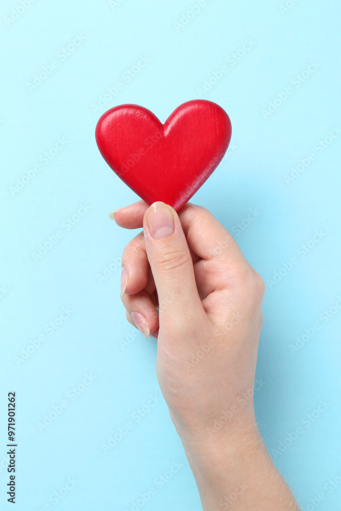 Woman with red heart on light blue background, closeup Woman with red heart on light blue background, closeup