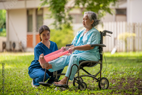 Healthcare or physical therapy nurse is helping elderly woman in performing a stretching or rehabilitation exercise with a resistance band caregiver individuals focused rehabilitation elderly concept.