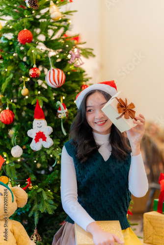 Beautiful young Asian woman happy with gift box This scene has a Christmas tree and a blurred background on New Year's Day.