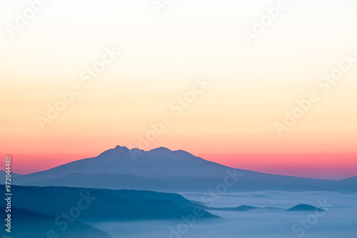 オレンジ色のグラデーションの空と遠くの山のシルエット。少し霞んだ雄大な自然の美しさ。