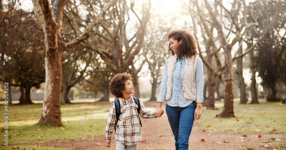 Fototapeta premium Holding hands, mother and child walking to school with safety, bonding and backpack in park together. Happy, woman and son on outdoor garden path for morning commute with love, trust and support.