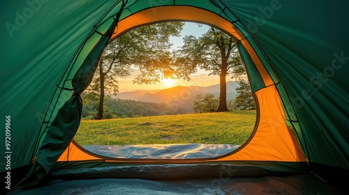 The serene perspective from inside a tent, looking out over a green field towards towering mountains in the distance photo