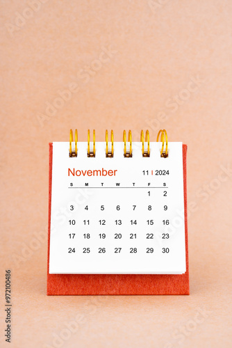 November 2024 white desk calendar on brown background.