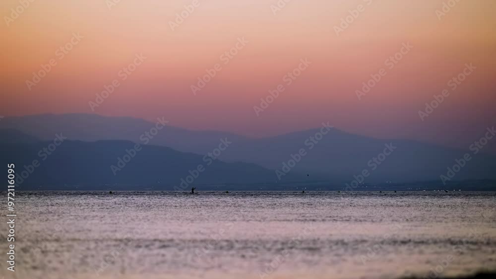 Scenic sunset view of the coastline of Almeria, Spain, with paddle boarders on the distance Scenic sunset view of the coastline of Almeria, Spain, with paddle boarders on the distance