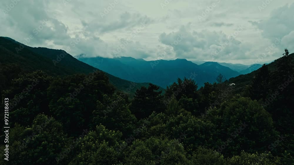 Aerial drone shot in the italian alps center europe of a mountain range with a cloudy sky and a forest in the foreground on a moody cloudy day. Aerial drone shot in the italian alps center europe of a mountain range with a cloudy sky and a forest in the foreground on a moody cloudy day.