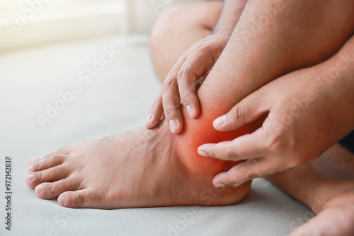 A man injured his ankle and it was swollen and red. Causes of pain include Ankle sprain, Gout, Rheumatoid arthritis, office syndrome, numbness, and cramp symptoms. Healthcare medical concept.