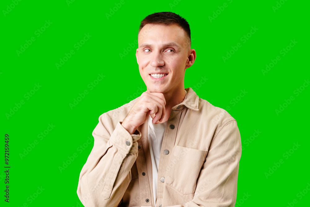 Young Man in Casual Attire Posing Thoughtfully Against a Bright Green Background Young Man in Casual Attire Posing Thoughtfully Against a Bright Green Background