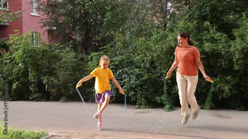 mom and child daughter jumping  over a rope in the yard near the house