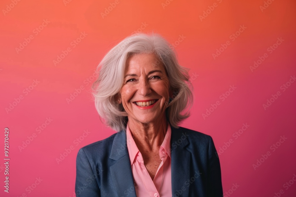 A cheerful senior woman in a blazer, smiling while presenting against a solid color backdrop, highlighting her confidence and experience in public speaking A cheerful senior woman in a blazer, smiling while presenting against a solid color backdrop, highlighting her confidence and experience in public speaking