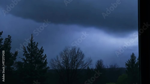 Dark storm clouds looming over a forest landscape
 photo