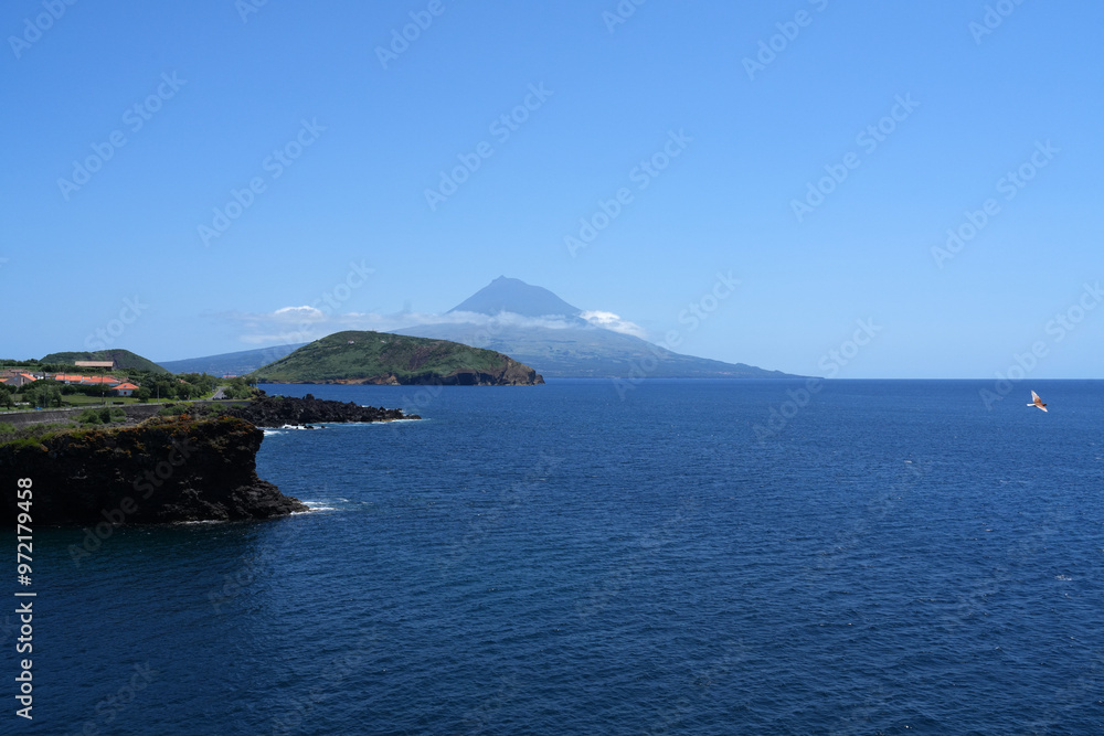 Fototapeta premium Der Vulkan Pico von der Nachbarinsel Faial aus über das Meer gesehen