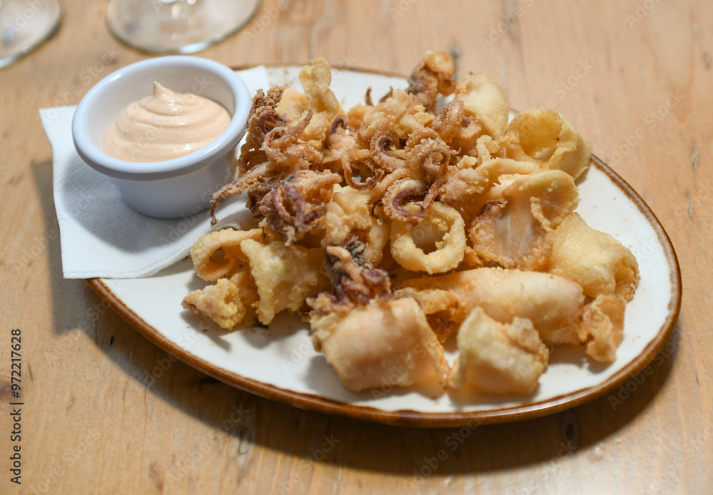 Una ración de calamares fritos con salsa de ajo en un restaurante europeo. Una ración de calamares fritos con salsa de ajo en un restaurante europeo.