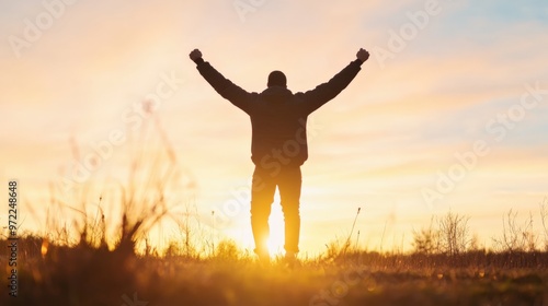 A silhouette of a person raising their arms in triumph against a beautiful sunset, symbolizing achievement and joy.