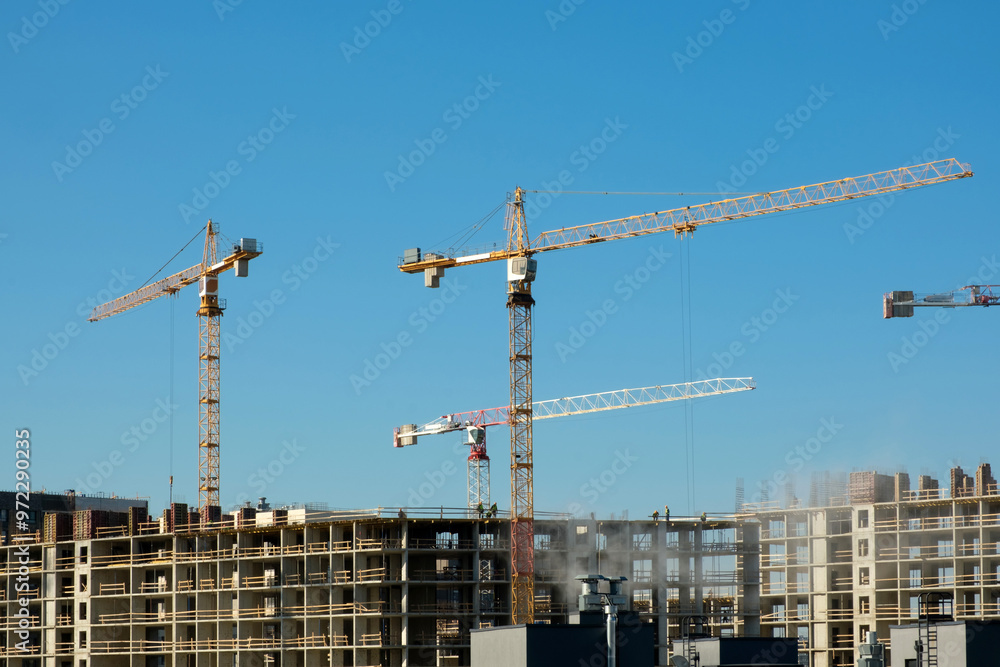 Large construction site with busy cranes. Summer blue sky. Large construction site with busy cranes. Summer blue sky.