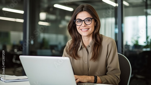 A confident businesswoman sitting at her desk and using a laptop.