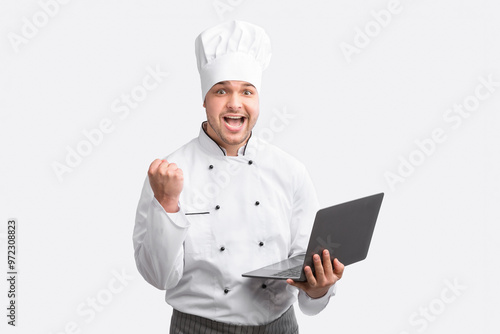 Culinary Success. Excited Cook Guy Holding Laptop Gesturing Yes Standing Over White Background. Studio Shot