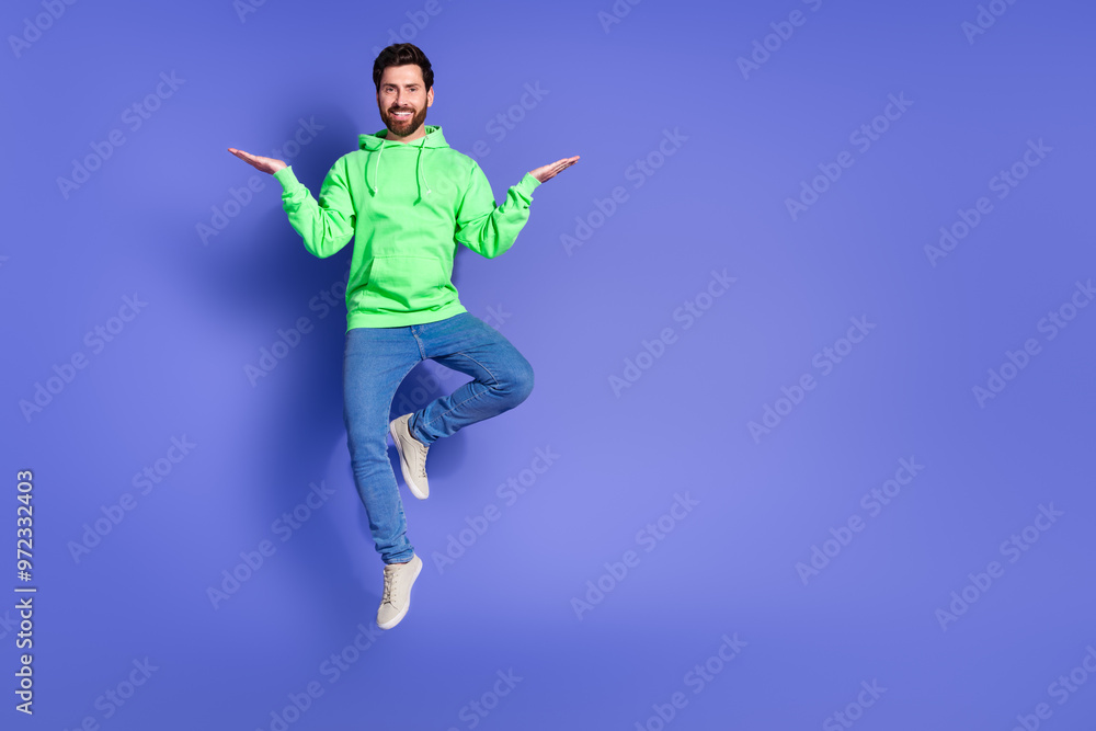 Full length photo of handsome young guy jump compare empty space dressed stylish green garment isolated on violet color background Full length photo of handsome young guy jump compare empty space dressed stylish green garment isolated on violet color background