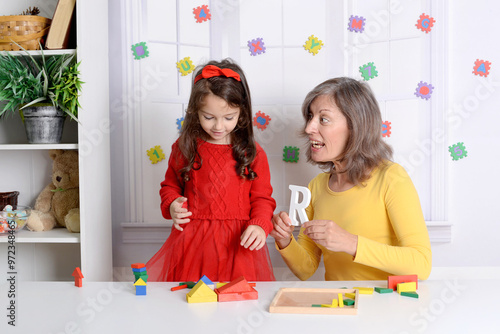 Grandma is playing with the alphabet child. It helps the girl learn a foreign language and improve her mental health and memory. Time spent together photo