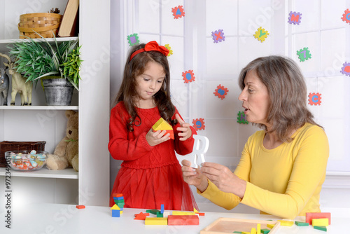 Grandma is playing with the alphabet child. It helps the girl learn a foreign language and improve her mental health and memory. Time spent together photo