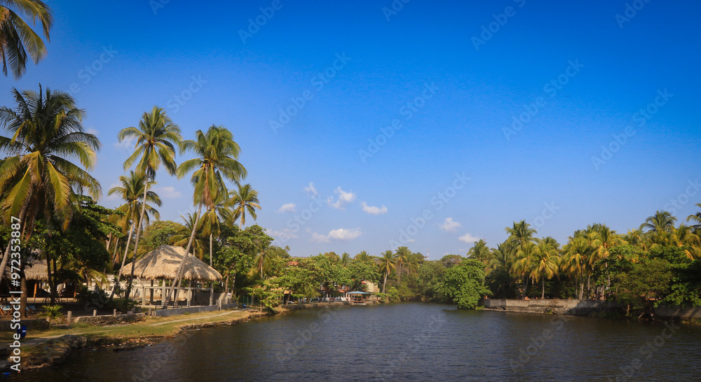 Breathtaking view of El Tunco's river surrounded by lush palm trees and clear blue skies in El Salvador Breathtaking view of El Tunco's river surrounded by lush palm trees and clear blue skies in El Salvador