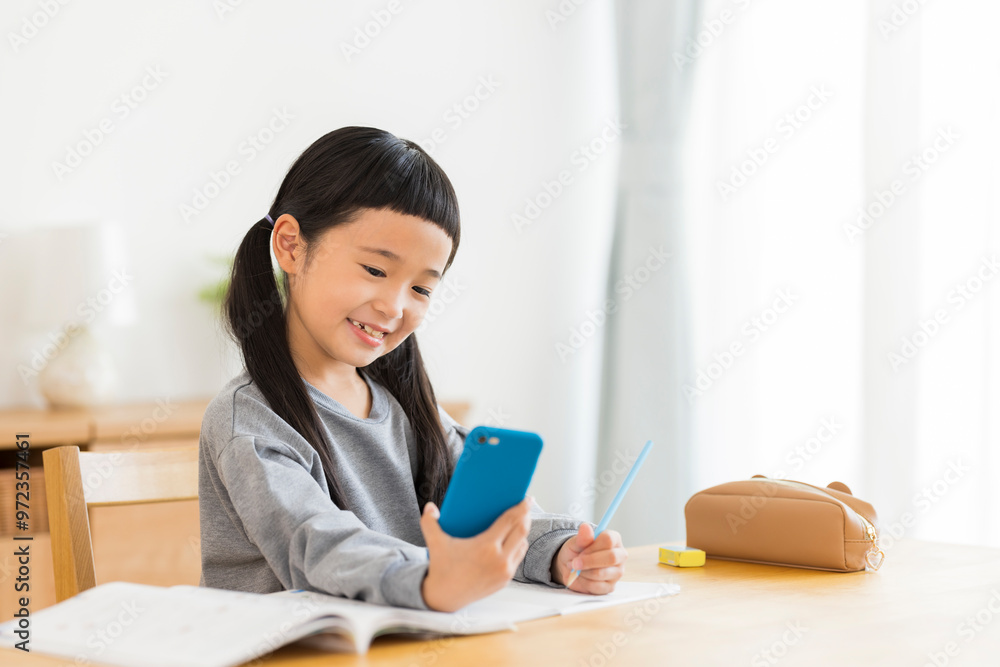 スマートフォンを見ながら勉強する女の子 スマートフォンを見ながら勉強する女の子