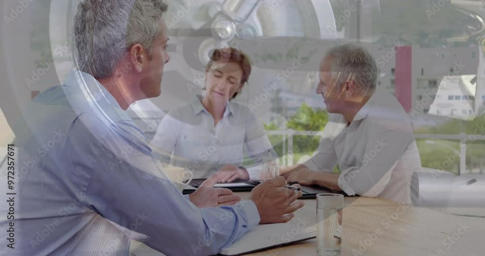 Animation of wheel over diverse colleagues discussing work in office Animation of wheel over diverse colleagues discussing work in office
