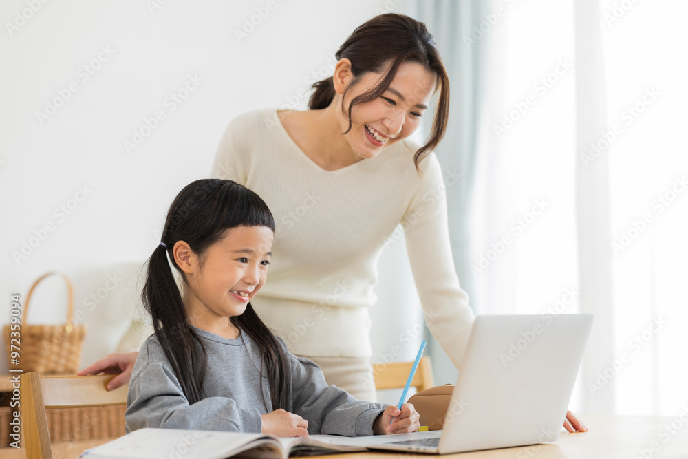 パソコンでオンライン学習をする女の子と母親 パソコンでオンライン学習をする女の子と母親