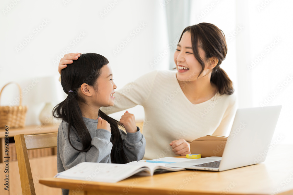 パソコンでオンライン学習をする女の子と母親 パソコンでオンライン学習をする女の子と母親