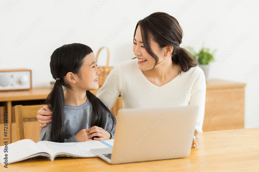 パソコンでオンライン学習をする女の子と母親 パソコンでオンライン学習をする女の子と母親