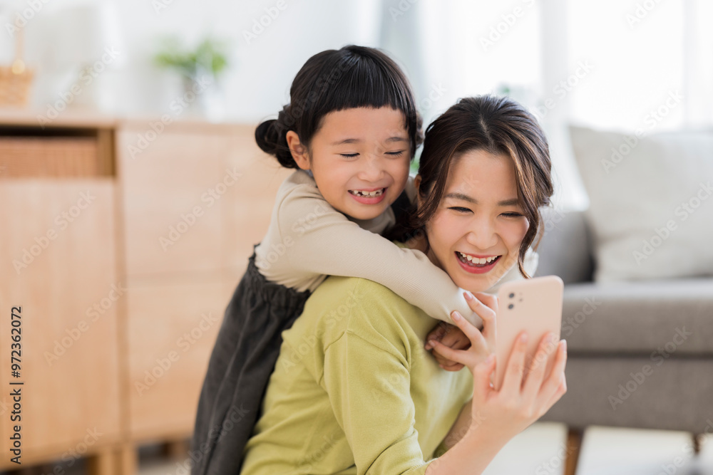 スマートフォンを見る母親に抱きつく女の子 スマートフォンを見る母親に抱きつく女の子
