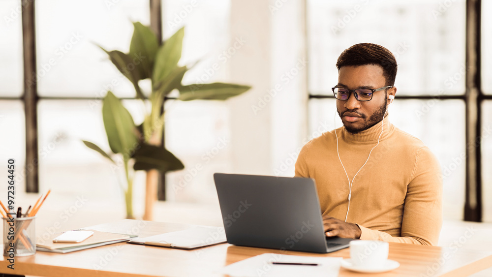 Distance Learning. Focused black student in glasses working on laptop preparing for an exam, panorama, copyspace Distance Learning. Focused black student in glasses working on laptop preparing for an exam, panorama, copyspace