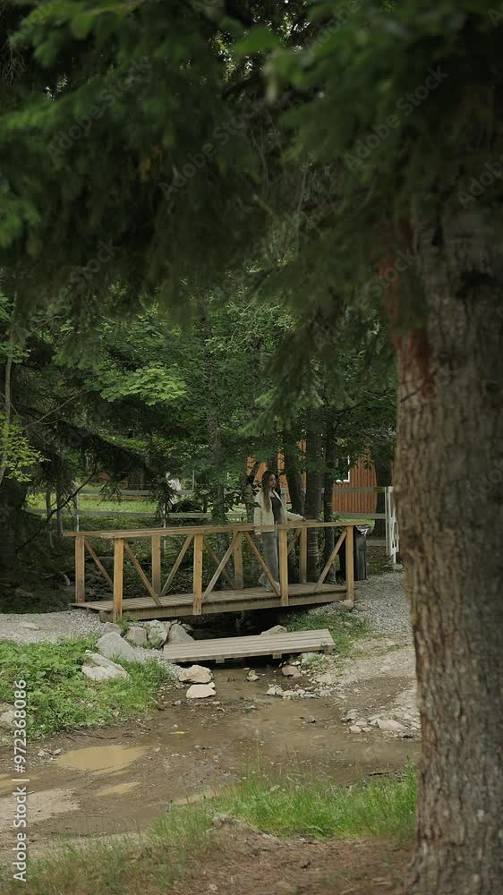 Woman Standing on a Wooden Bridge in Forested Area Woman Standing on a Wooden Bridge in Forested Area