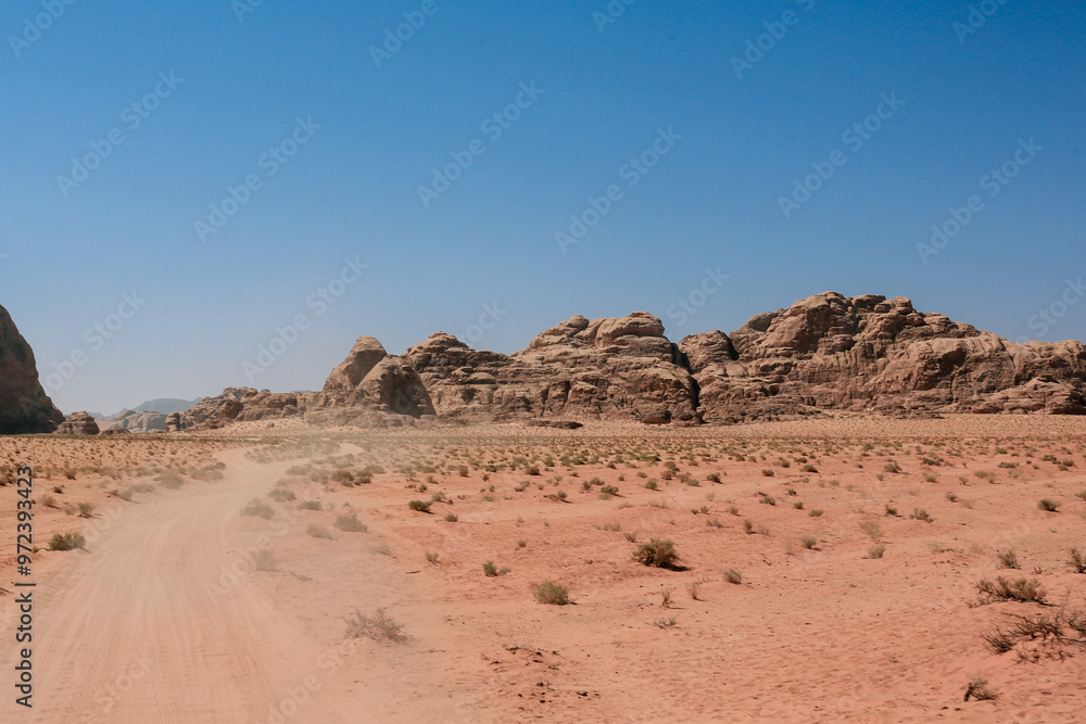 Exploring the stunning landscapes and rugged terrain of Wadi Rum Desert in Jordan under a clear blue sky Exploring the stunning landscapes and rugged terrain of Wadi Rum Desert in Jordan under a clear blue sky