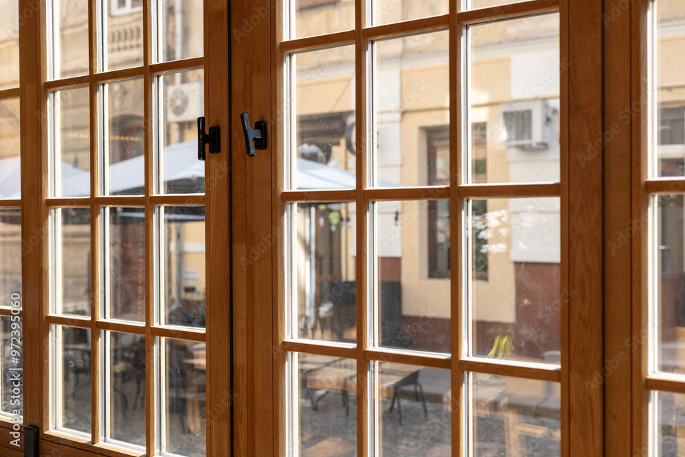 Cozy cafe interior with large wooden windows overlooking a bustling outdoor terrace in spring Cozy cafe interior with large wooden windows overlooking a bustling outdoor terrace in spring
