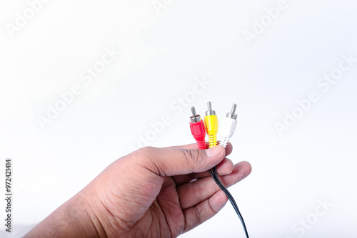 hand holding red, yellow and white RCA plugs with black cables isolated on white background.